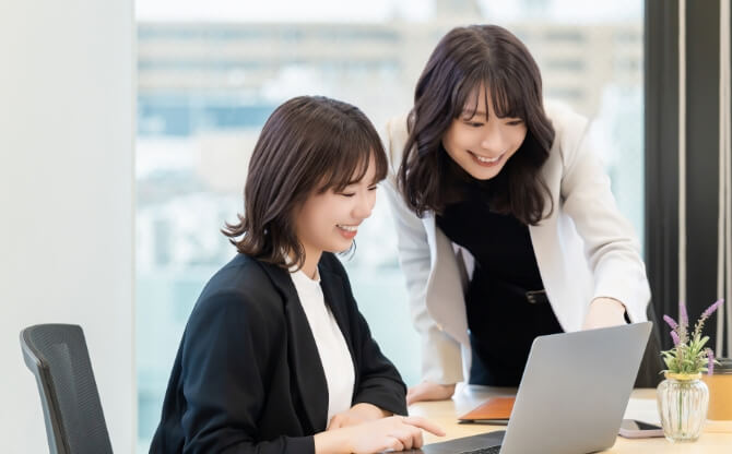 パソコンを使って教務課・就職課の担当者からアドバイスを受ける女性のビジネスシーン