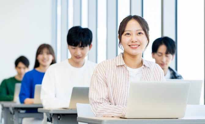 専門学校の授業時間内で実施される採用活動に参加する学生たち。ノートパソコンを使って笑顔で学ぶ様子。